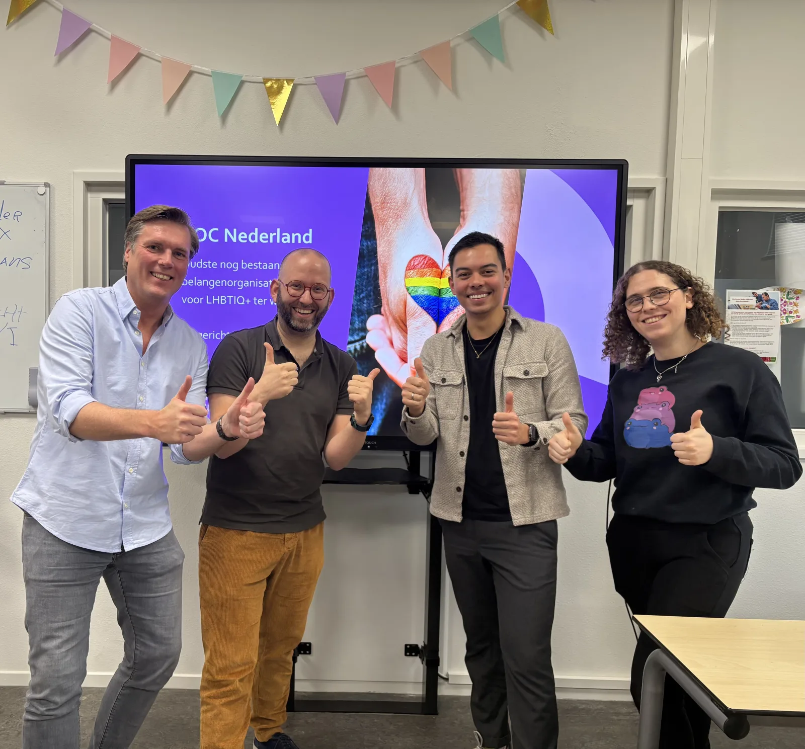 Vier voorlichters voor een scherm met een presentatie van COC Nederland.